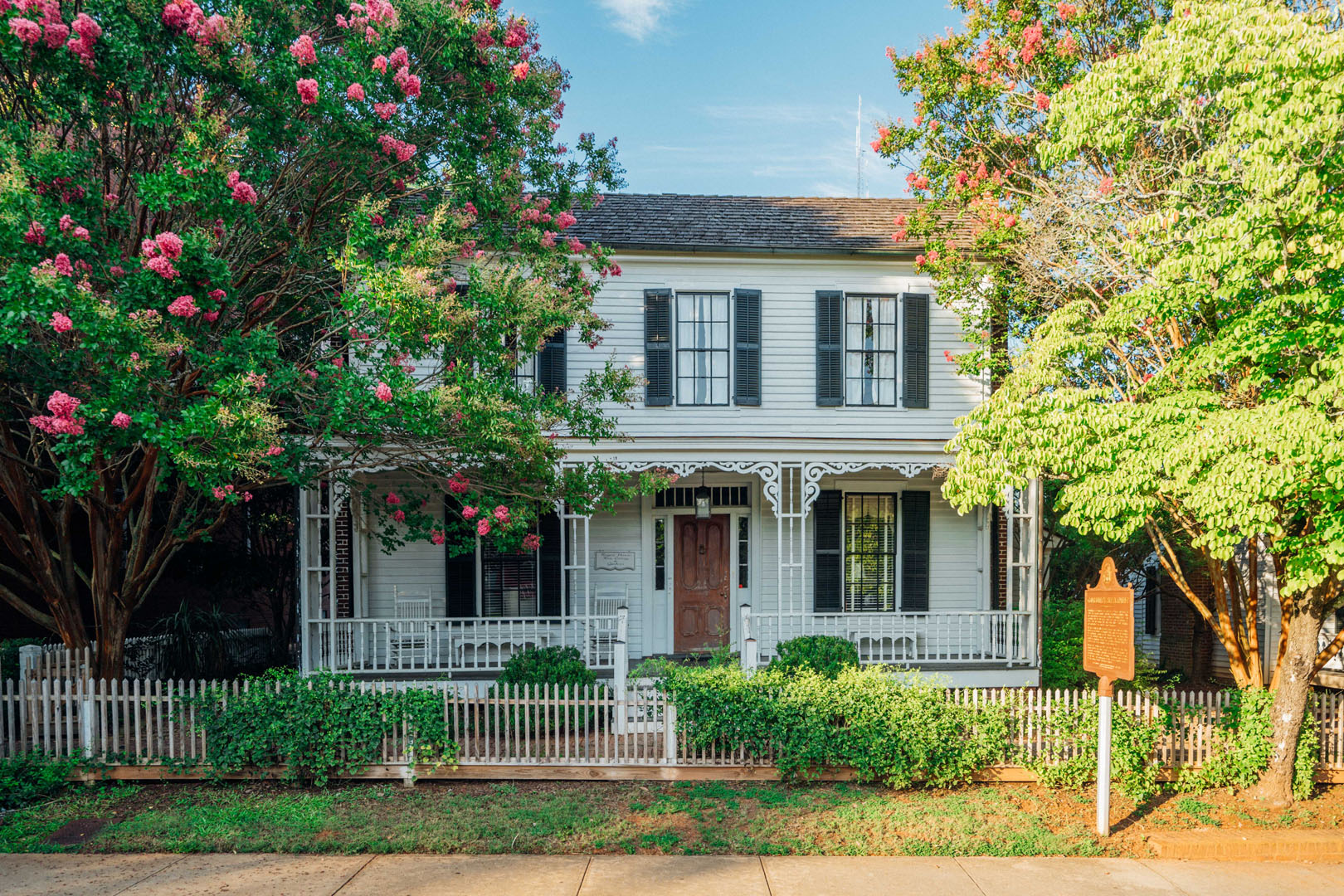 photo of Rogers House, a white Piedmont-plain style home surrounded by trees in bloom