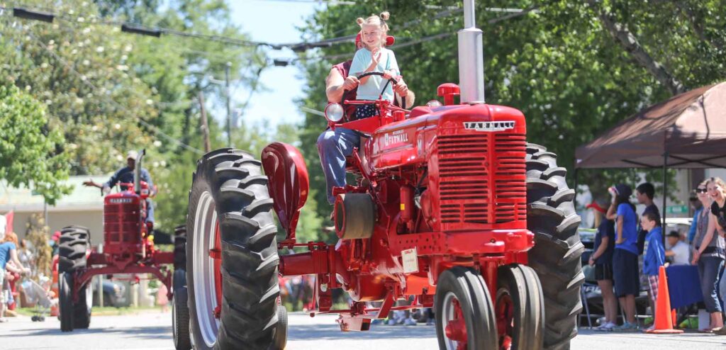 A girl waves from a tractor in the Bostwick Cotton Gin Festival's parade