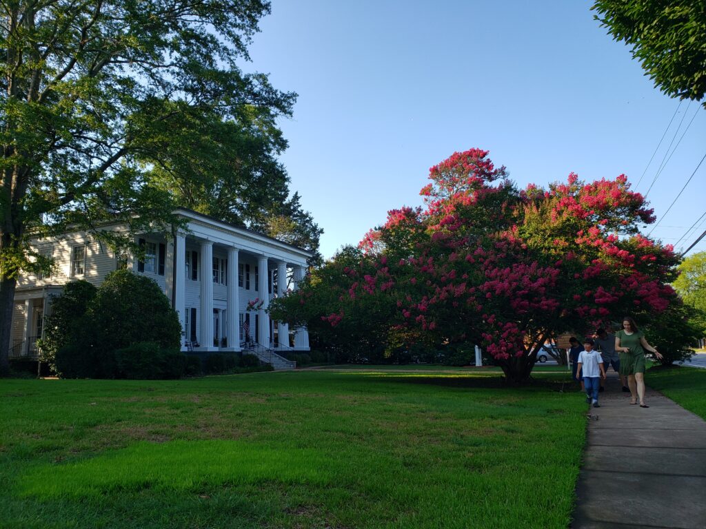 a side view of Heritage Hall from the sidewalk where a woman and child are walking